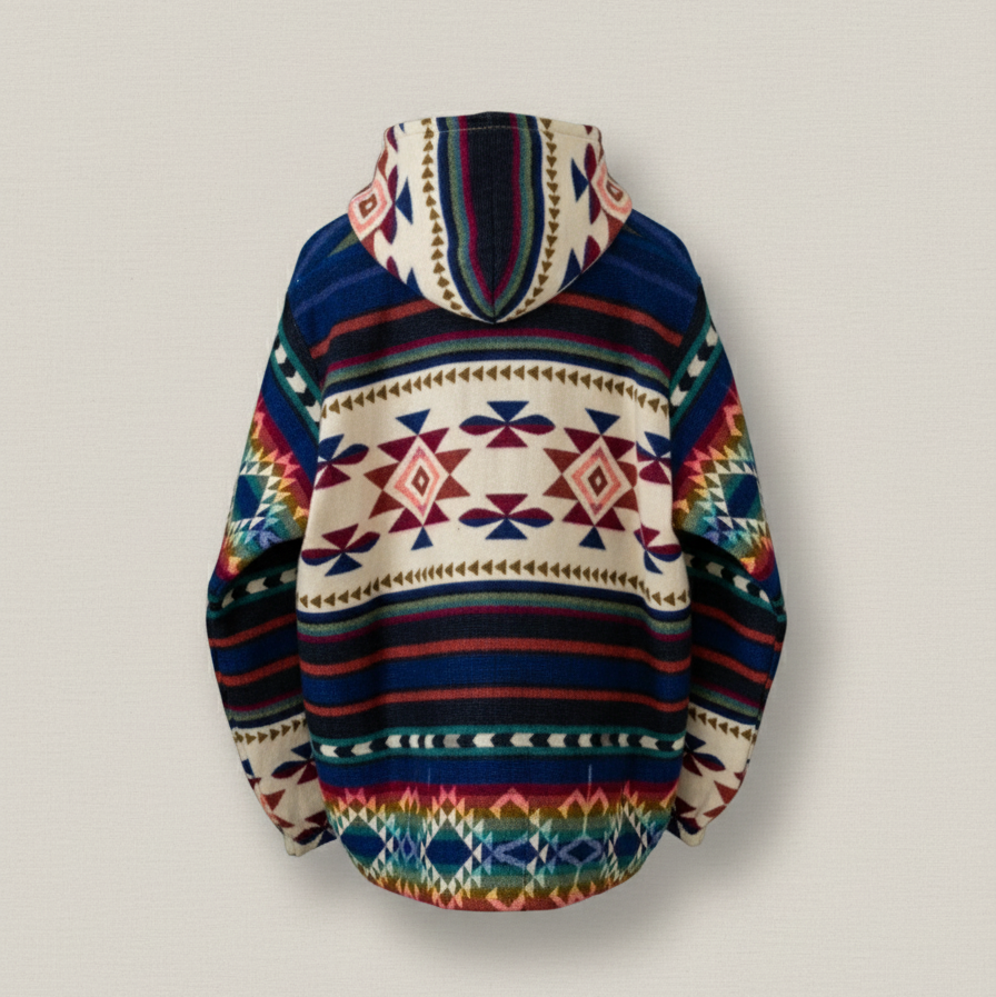 Back view of the ANKA boho jacket made from a wool blend with alpaca, showing colorful geometric Andean patterns in red, blue, green, and cream, photographed against a solid cream background.